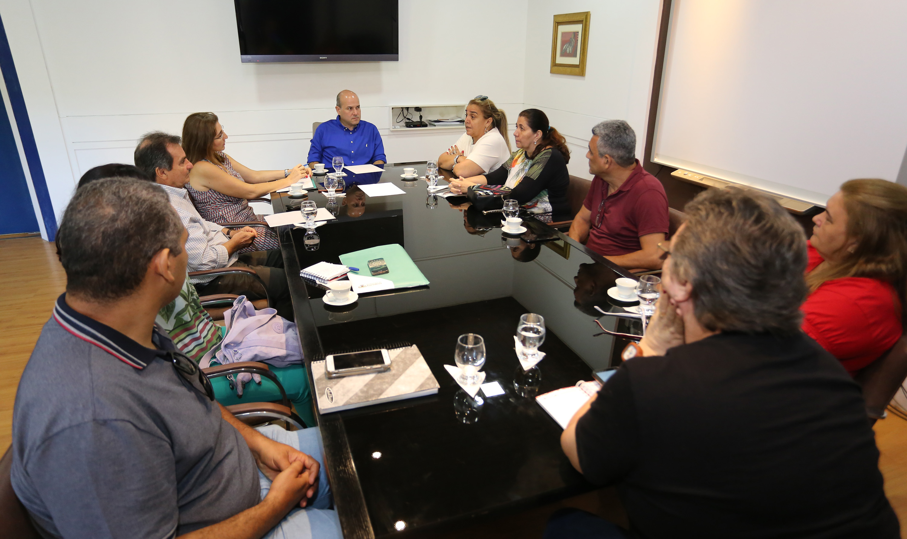 prefeito e outras pessoas sentadas ao redor de mesa conversando